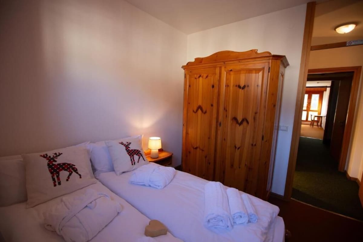 A hotel room with a bed, a wardrobe, and a nightstand with a lamp.