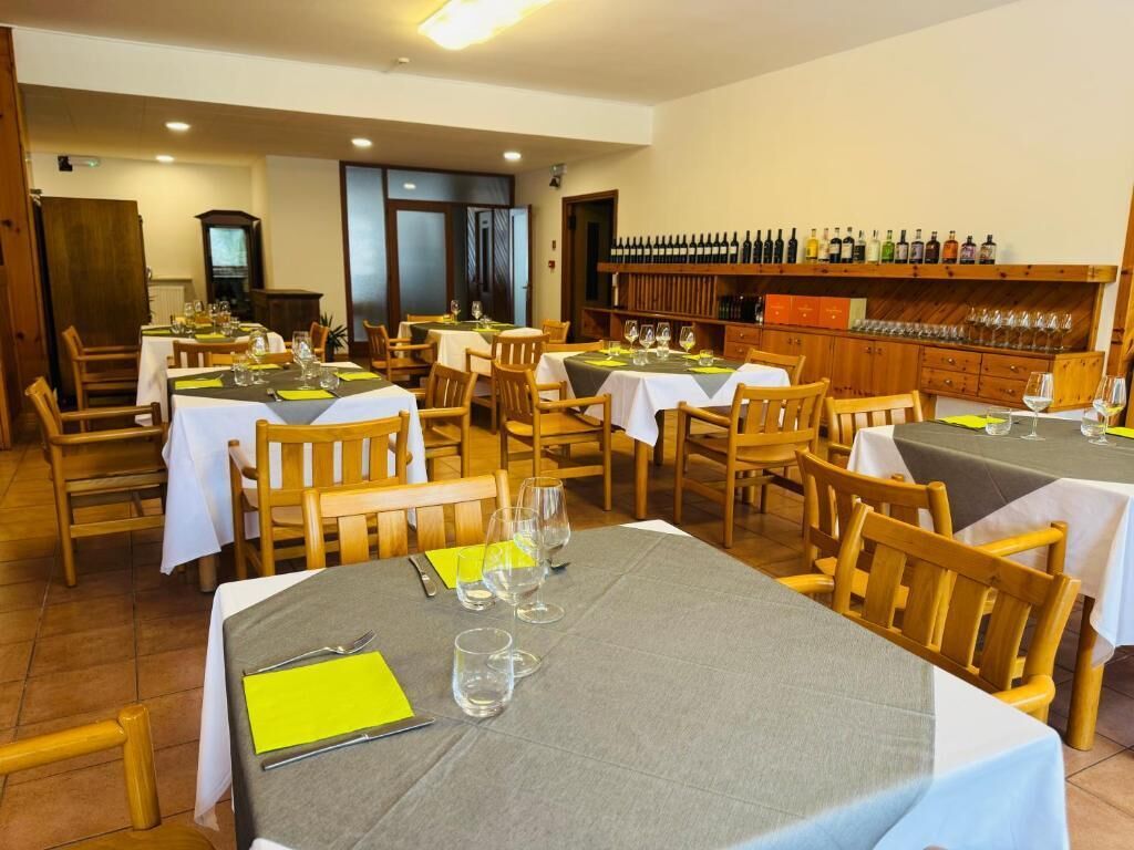 Un ristorante con diversi tavoli, sedie e una cantina piena di bottiglie.