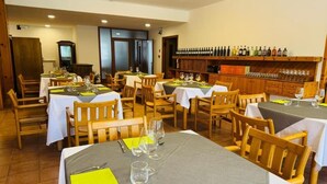 A restaurant with multiple tables, chairs, and a wine rack with bottles. - Bike & Bikers Hotel (Ampezzo)