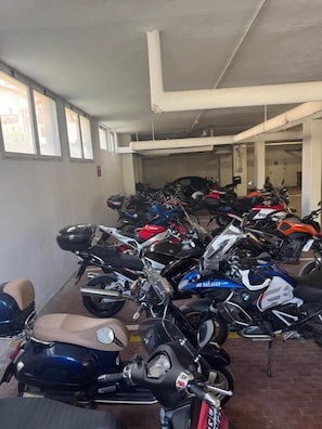 Un garaje para estacionar con varias motocicletas y scooters organizados en filas.