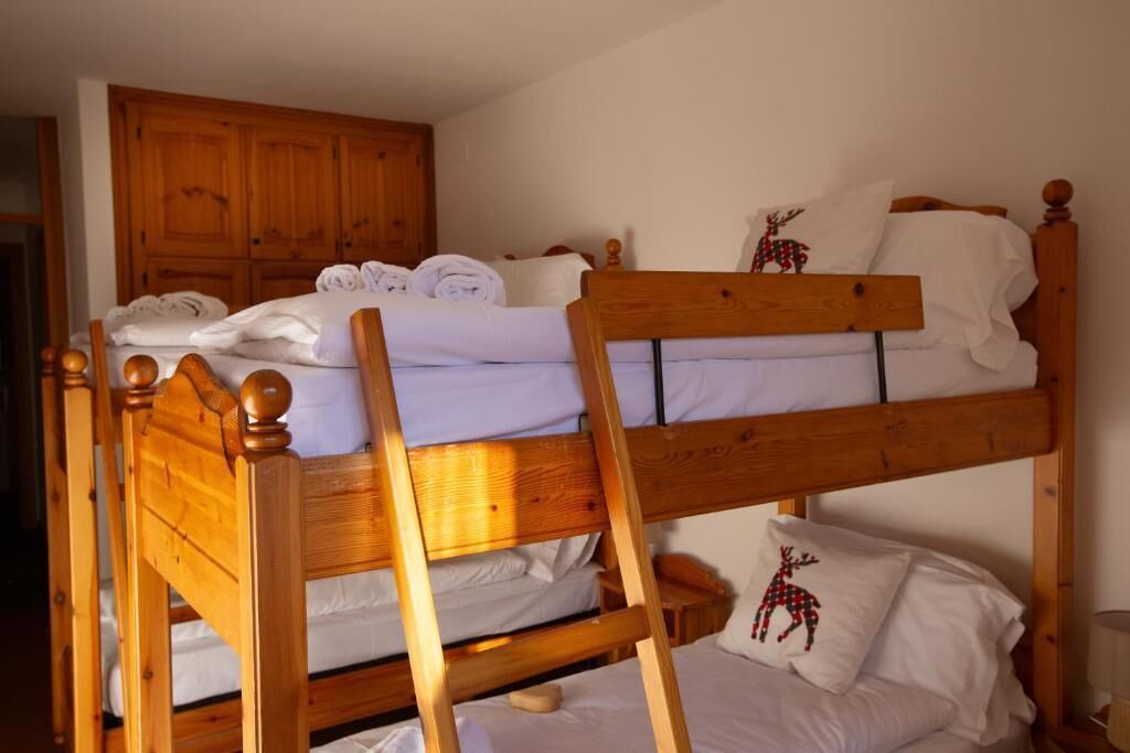 Una cama litera con cabeceros de madera y un armario de madera al fondo.