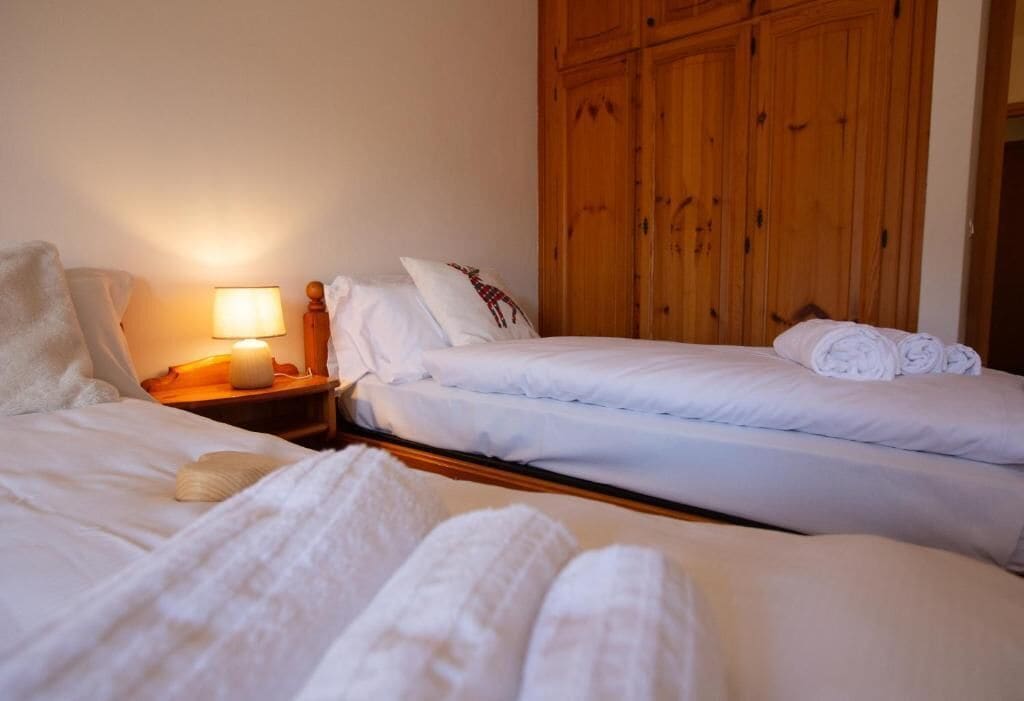 Ein Hotelzimmer mit zwei Betten, einem Nachttisch mit Lampe und Holzschränken.