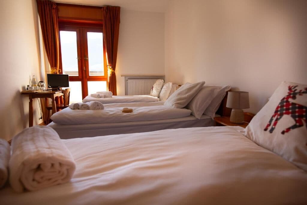Une chambre d’hôtel avec deux lits, un bureau avec un ordinateur et une fenêtre avec des rideaux.