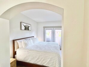 A bedroom with a bed, a framed picture on the wall, and a window with a view. - 2073 | Designer King Villa | Full Kitchen | Pool (Midway)