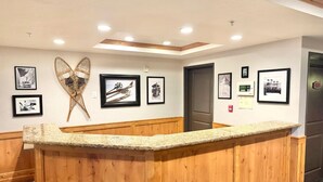 A reception area with a wooden counter, framed photographs on the wall, and a ceiling with recessed lighting. - 2073 | Designer King Villa | Full Kitchen | Pool (Midway)