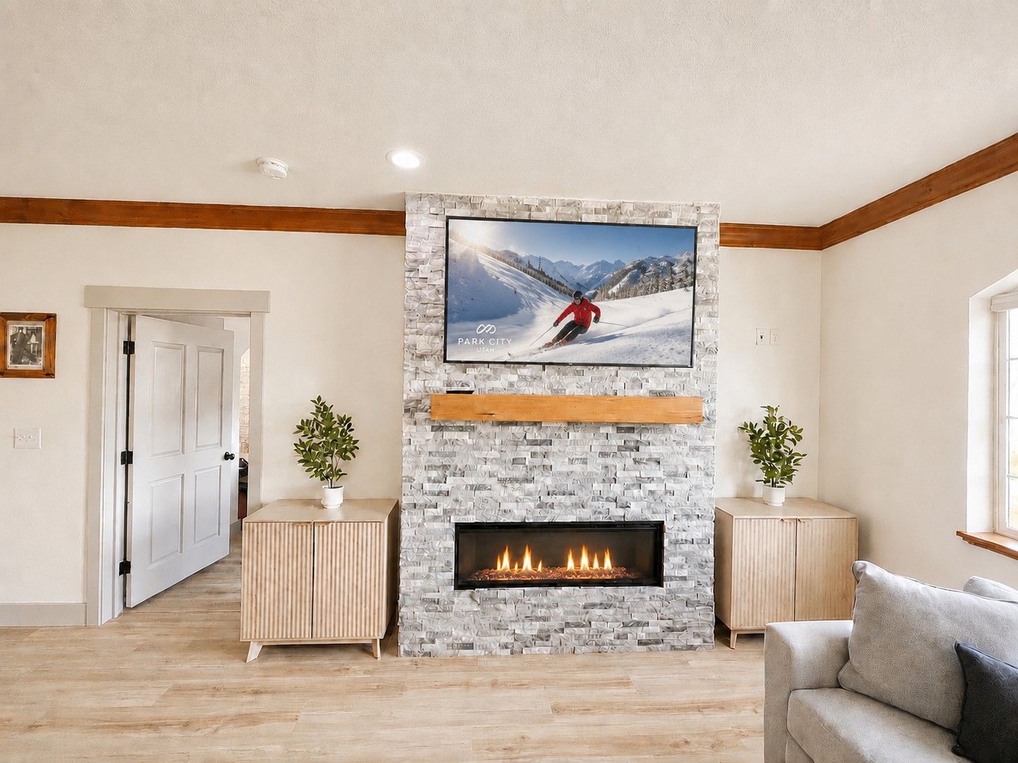 A living room with a fireplace, a mounted TV, and a door leading to another room.