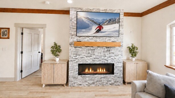 A living room with a fireplace, a mounted TV, and a door leading to another room. - 2073 | Designer King Villa | Full Kitchen | Pool (Midway)