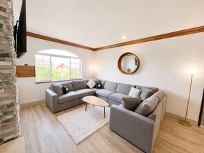 A modern living room with a sectional sofa, a small coffee table, a round mirror, and a floor lamp. - 2073 | Designer King Villa | Full Kitchen | Pool (Midway)
