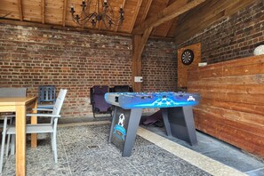 Una habitación con mesa de fútbol de mesa, dardo y pared de ladrillo.