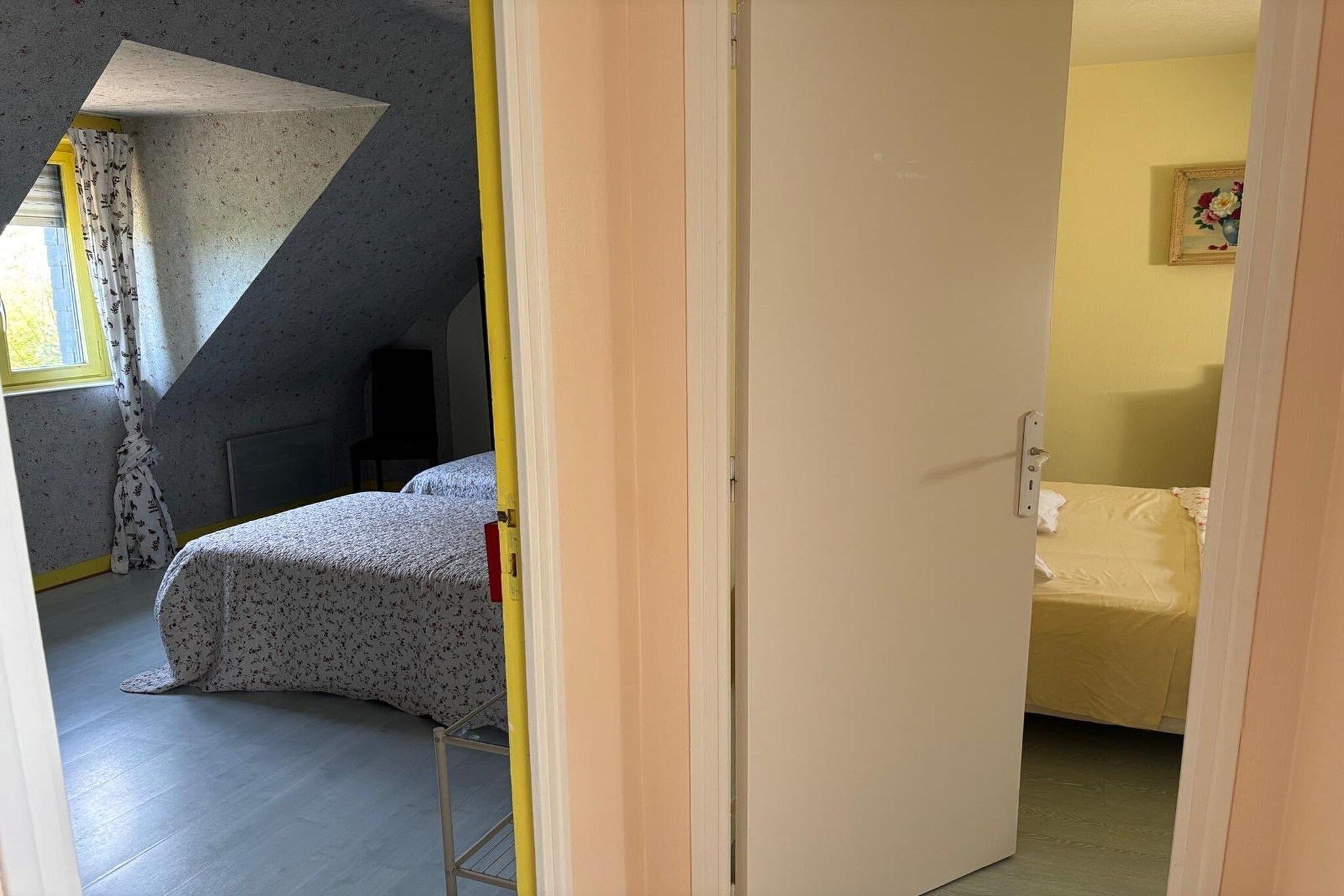 A room with a bed, a chair, a door, and a painting on the wall.