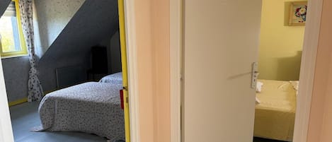 A room with a bed, a chair, a door, and a painting on the wall.
