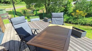 Eine Holzterrasse mit Tisch und zwei Stühlen.