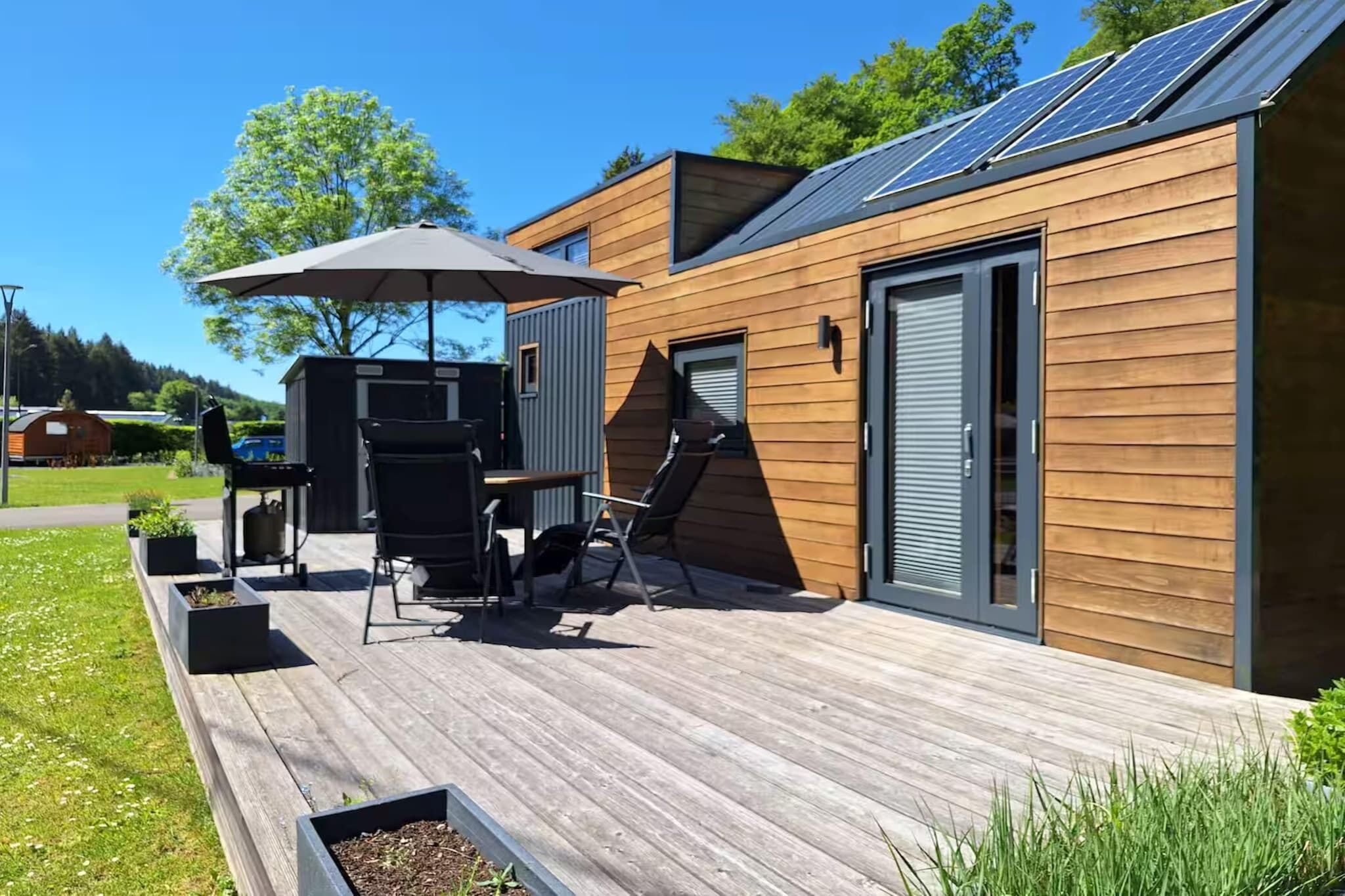 A modern house with a deck, outdoor furniture, and solar panels.