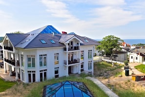 A multi-story house with a large balcony, a swimming pool, and a view of the sea. - Studio in Heringsdorf mit gemeinsamen Innenpool (Ostseebad Heringsdorf)
