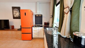 A compact kitchen with a refrigerator, microwave, sink, and a small countertop. - AP433 VILLA LA NORIA (Nerja)