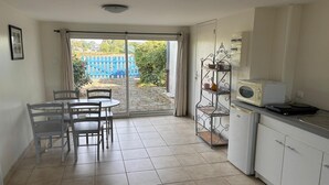 Una cucina con zona pranzo, una porta scorrevole in vetro che si apre su un giardino e un forno a microonde sul piano di lavoro.