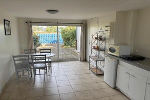 Eine Küche mit Essbereich, einer Schiebetür zu einem Garten und einer Mikrowelle auf der Arbeitsplatte.