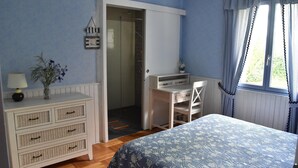 Una camera da letto con un letto, una scrivania, un comò e una porta che dà sul bagno.