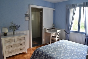 Ein Schlafzimmer mit einem Bett, einem Schreibtisch, einer Kommode und einer Tür zu einem Badezimmer.