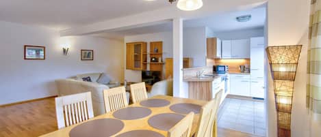 Un espacio habitable moderno con comedor, cocina y un pasillo que conduce a un dormitorio.