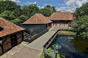 A traditional wooden building with a water wheel, a brick pathway, and a canal. - Langelshoes Guesthouse (Haaksbergen)
