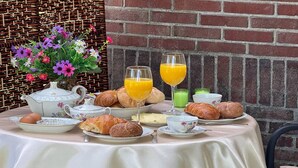 Une table mise pour le petit-déjeuner, avec des croissants, une théière, des tasses et un vase rempli de fleurs.