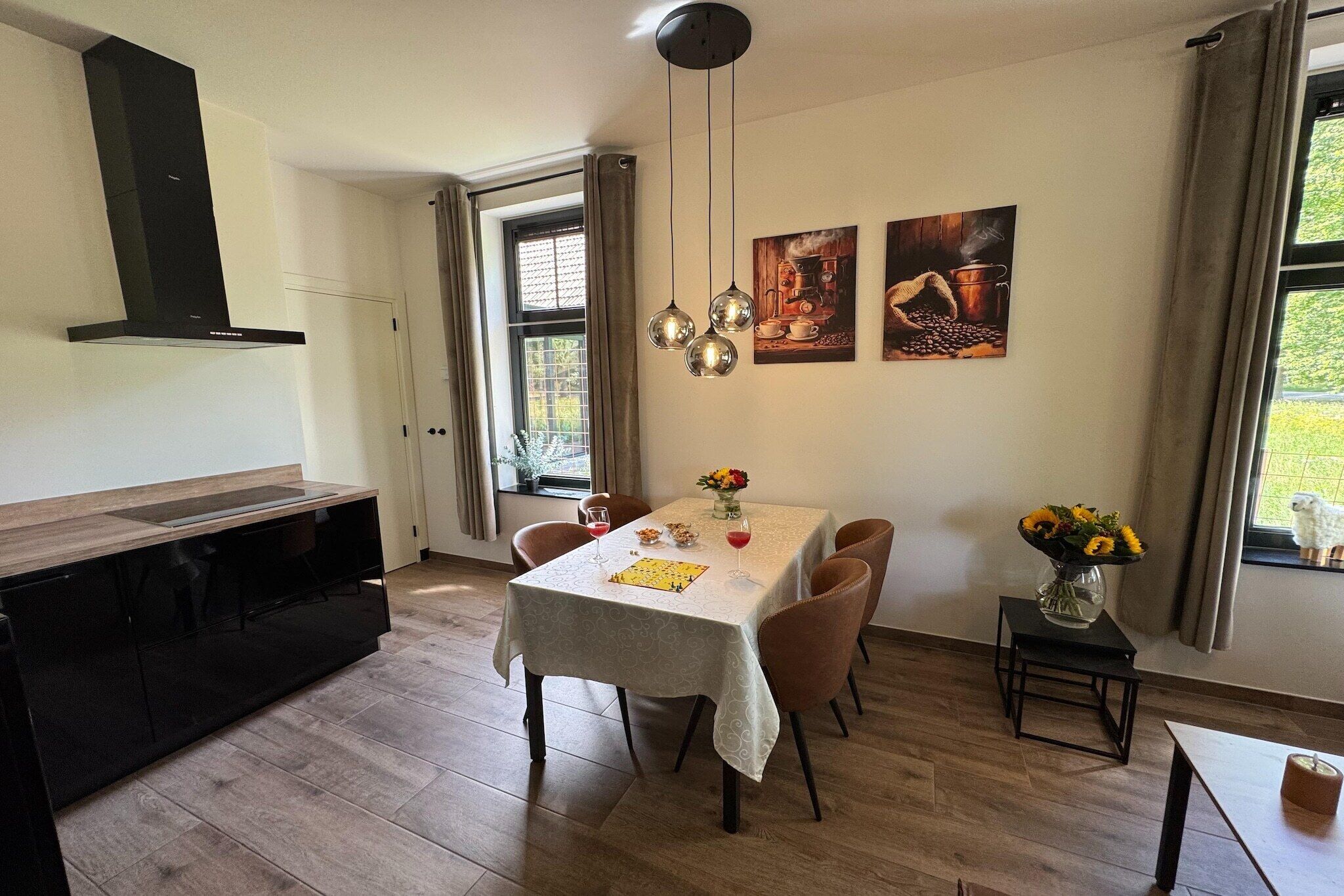 A dining area with a table set for four, a black cabinet, and two wall-mounted pendant lights.