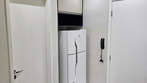 Casa de banho com bancada de granito preto, portas brancas e telefone preto fixado na parede.