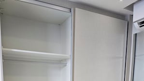 Um closet amplo com porta deslizante, barra de metal e prateleira.