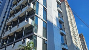 Um edifício de vários andares com design arquitetônico moderno, com varandas e grandes janelas.