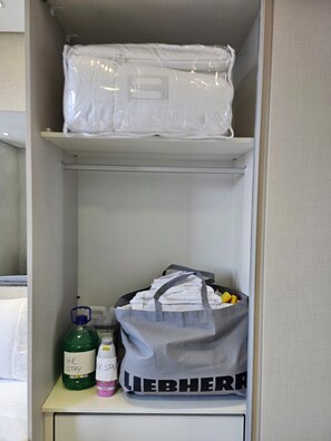 A storage area with a suitcase, a bottle, and a bag labeled 'LIEBHERR' on a shelf. - Fully equipped studio in a great location in Alphaville | Selenita #19 (Barueri)