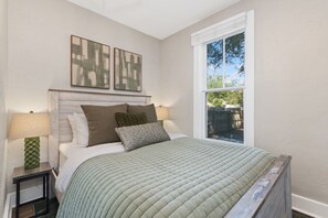 A bedroom with a bed, two bedside lamps, a window, and two wall-mounted artworks. - Akin East Pet-friendly Furnished Monthly Rental (Fort Collins)