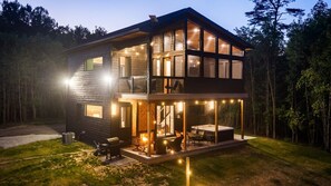 Eine zweistöckige Holzhütte mit Balkon, Sitzgelegenheit im Freien und Whirlpool.