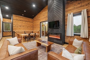 A modern interior with a fireplace, wooden walls, a TV, and a dining area. - Escape to Nature's Wonderland: The rolling  foothills of Appalachia (Logan)