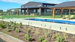 Ein modernes Gebäude mit Schwimmbad und überdachter Terrasse.