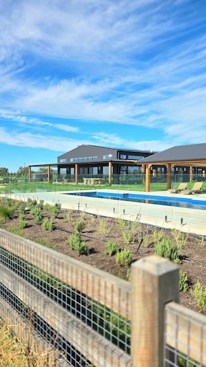 Een modern gebouw met een zwembad en een overdekt terras.