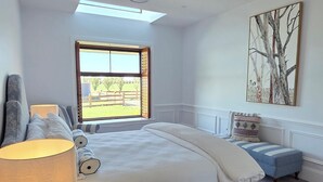 Ein Schlafzimmer mit einem Bett, einem Nachttisch, einer Lampe, einem Deckenventilator, einem Fenster und einem Gemälde.