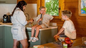 Une cuisine avec des murs en bois, une fenêtre et une table sur laquelle se trouvent des fruits et une machine à café.