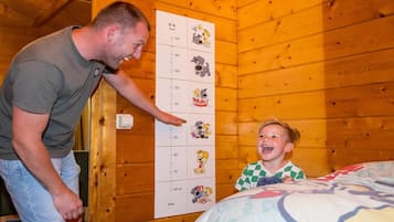 A man and a child in a wooden room with a height chart on the wall.
