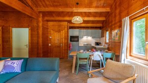 L'intérieur d'un chalet en bois comprend un coin repas, une petite cuisine et un canapé.