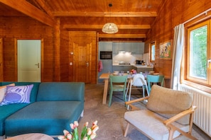 Interno di una baita in legno con zona pranzo, angolo cottura e divano.