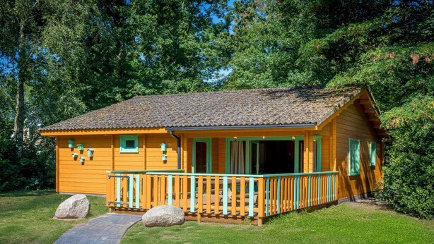 Une cabane en bois dotée d’un porche et d’un chemin menant à l’entrée.
