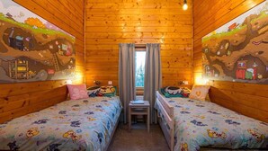 Une cabane confortable avec deux lits, une petite table et une fenêtre avec des rideaux.