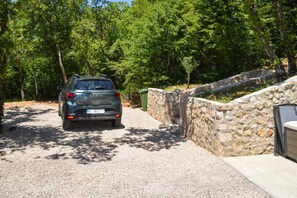 A parked car in a driveway with a stone wall and trees in the background. - Nice home in Grižane-Belgrad with garden (Grižane-Belgrad)