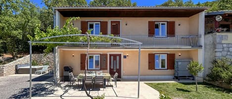 A two-story building with a covered patio area, outdoor seating, and a small garden.