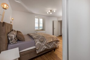 A bedroom with a bed, a nightstand, a window, and a door. - Nice home in Grižane-Belgrad with garden (Grižane-Belgrad)