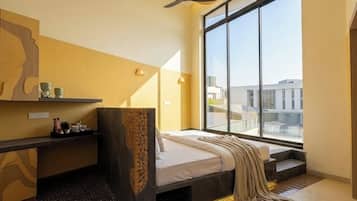 A modern bedroom with a large window, a bed, a desk, and decorative wall art.