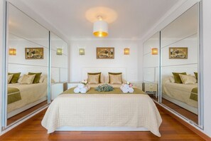 A bedroom with a large bed, two bedside tables, a mirror, and wall-mounted lights. - Ocean Dream House (Costa Adeje)