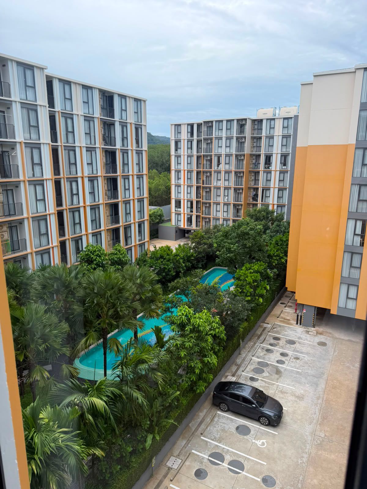 A residential building with multiple floors, a swimming pool, and a parking area.