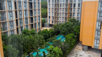 A residential building with multiple floors, a swimming pool, and a parking area.